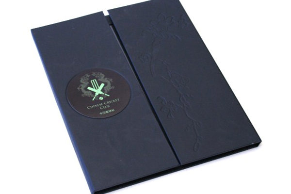 We used a new design for this menu consisting of a bonded leather outer covering and a hinged opening on the centre of the folder. Inside the menus hold 1 x A4 page on the back panel and 2 x half A4 pages on the left and right inside cover. We branded the menu using an aluminium circular badge with a self adhesive backing to affix it to the front left hand panel.